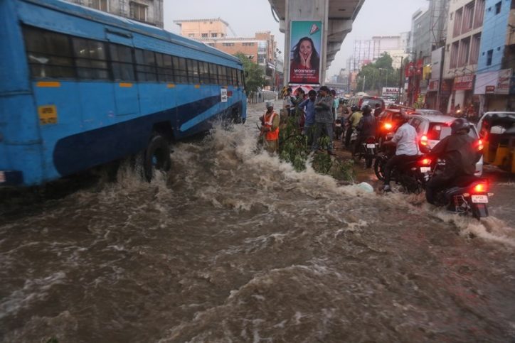 A bus splashes drives past a flooded street in the rain in Hyderabad.